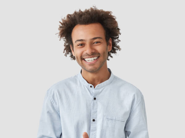 Image of young man with curled hair smiling at camera